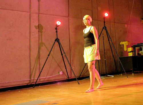 A woman walking in a gym with cameras recording