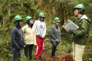 People wearing warm clothes and hard hats standing in a forest