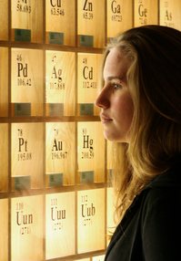 A woman looking at a periodic table of elements