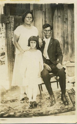 A girl and her parents outside their house