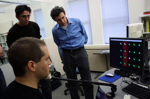 Three men observe a computer