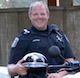 A man in a police uniform, holding a motorcycle helmet