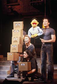 A man on stage with a puppet and two other actresses