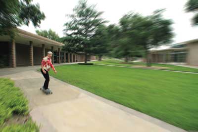 A woman longboarding down a sidewalk