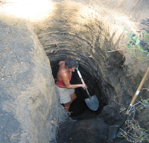 A woman with a shovel in a deep hole