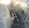 A woman with a shovel in a deep hole