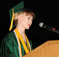 A woman wearing a cap and gown, standing at a podium